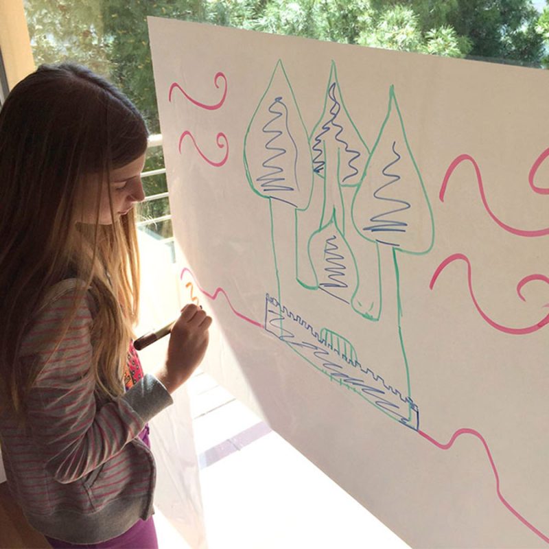 Children drawing picture on smart whiteboard sheet stuck on glass